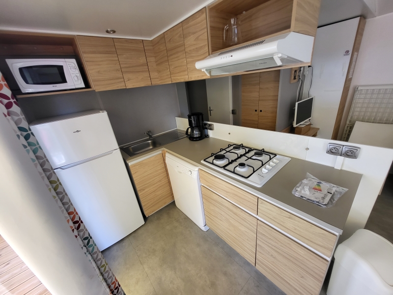 Cuisine équipée dans mobil-home avec plaque gaz, lave-vaisselle et réfrigérateur congélateur, hotte...