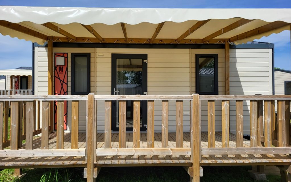 Mobil-home vue de face avec terrasse en bois couverte avec bâche de toit